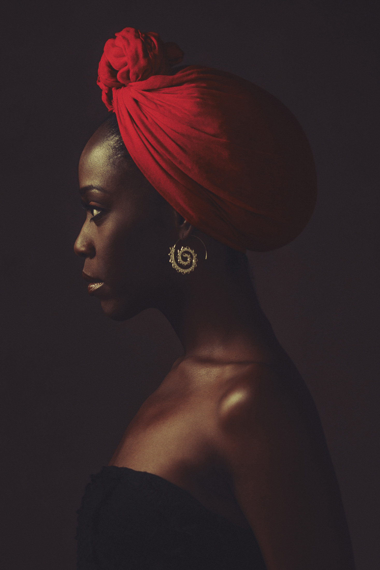 Profile portrait with a red head wrap on a dark canvas, AJK Images Dallas